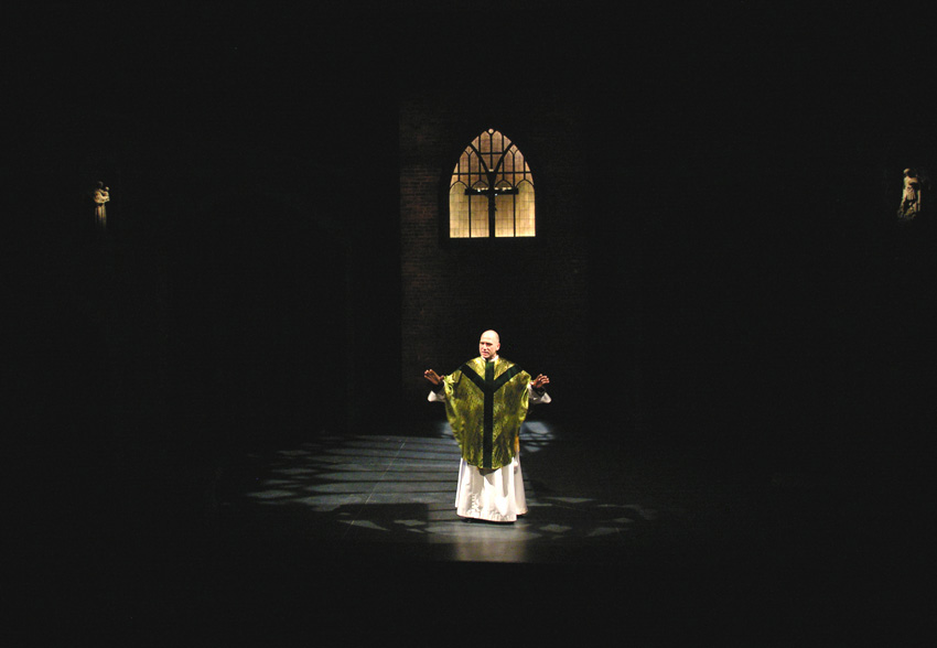 Father Flynn sermonizes in light from a high church window