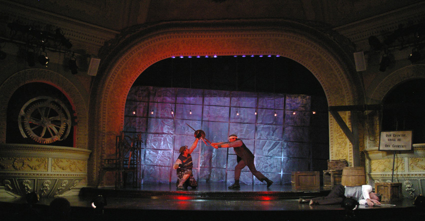 the battles rage, with blue background and red footlights